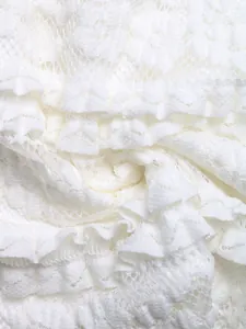 Détail macro de dentelle blanche délicate avec volants étagés et texture maille florale