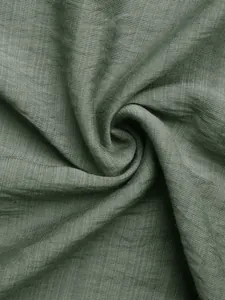 Detailed macro view of dark green pleated fabric texture with premium linen weaving