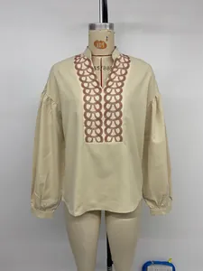 Detail of beige stand collar blouse featuring brown chain pattern and puff sleeves