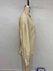 Close-up of vintage embroidery details and puffy lantern sleeves on a beige blouse