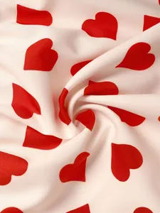 Detail of pink fabric with red heart pattern showing soft texture and spiral drapes