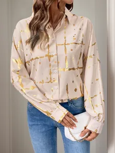 Dettaglio della camicetta beige a maniche lunghe con stampa geometrica in lamina d'oro