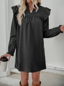 Detail of black dress with ruffled stand collar, V-neck, and textured fabric finish