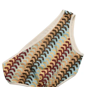 Close-up of crochet hollow knit fabric with colorful wave patterns and soft beige piping