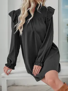 Detail view of layered ruffles on the shoulder of a black long-sleeved dress