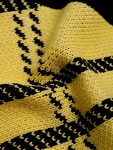 Detailed close-up of yellow and black geometric knit texture on a V-neck sweater vest
