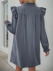 Detail view of the back ruffle trim and pleated design on this dusty blue long sleeve dress