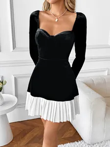 Detail of velvet mini dress showing white pleated hem and elegant black contrast fabric