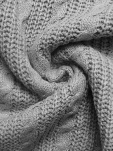 Vista macro di tessuto a maglia a trecce grigio con trama dettagliata e fibre di lana