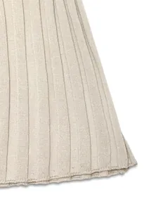 Vue macro de l'ourlet de la robe en maille beige avec texture raffinée à côtes verticales