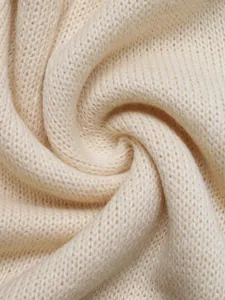 Macro d'une maille crème douce avec des fibres duveteuses et une texture de pliage