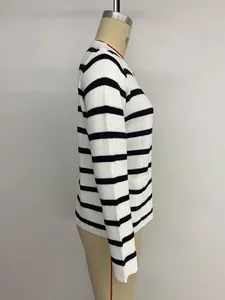 Détail d'un cardigan en maille à rayures noires et blanches avec bouton en métal
