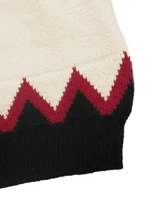 Close-up of zigzag pattern knit sweater with cream, burgundy, and black ribbed hem detail