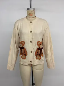 Détail de jacquard d'ours sur gilet en maille crème avec nœud 3D rouge et des boutons
