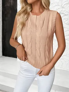 Detail of cable knit pattern and ribbed hem on a peach sleeveless sweater vest