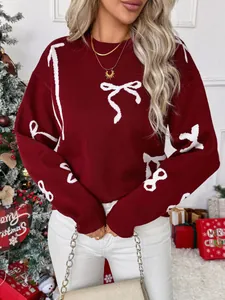 Close-up of burgundy crewneck sweater featuring white bow jacquard and ribbed cuffs