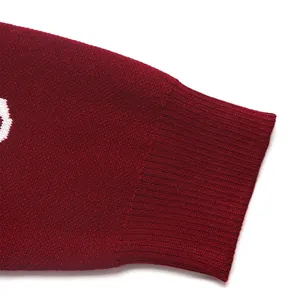 Detail of red knit sweater featuring ribbed cuffs and white jacquard pattern textures
