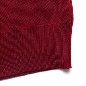 Close-up of red knit sweater featuring a dense texture and ribbed hem detail