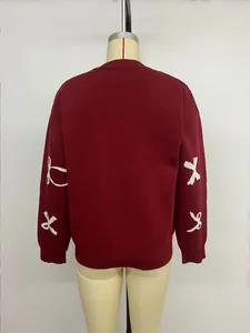Detail of burgundy knitted sweater with white bow embroidery and ribbed sleeve cuffs