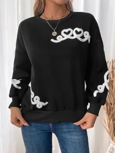 Close-up of white towel embroidery heart patterns on a black fleece sweatshirt