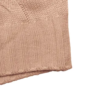 Detail of solid color cable knit texture and ribbed hem on a sleeveless sweater vest