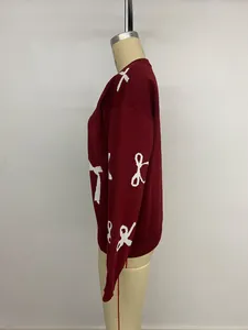 Detail view of red knitted sweater featuring white bow jacquard and ribbed cuffs