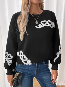 Detail of white 3D heart embroidery and textured towel stitch on a black sweatshirt