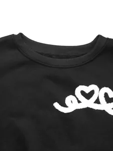 Detail of crew neck sweatshirt with white heart towel embroidery on black cotton fabric