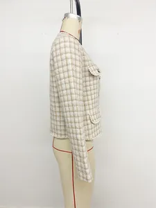 Detail van tweedtextuur en witte parelafwerking op het elegante slanke korte vest