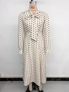 Dettaglio dell'elegante scollo a fiocco e della stampa a pois neri sull'abito a maniche lunghe