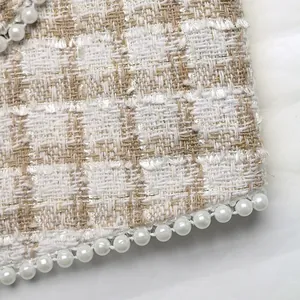 Close-up van elegante tweedstof met gouden glinstering en witte parelversieringen
