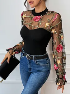 Close-up of sheer mesh sleeves featuring vibrant floral embroidery and ruffled cuffs