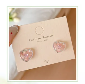 Détail macro de boucles d'oreilles cœur rose avec cristal sur clous en argent