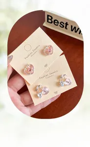 Vue détaillée des boucles d'oreilles cœur rose et pendentifs cerise sur présentoir