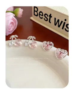 Détails macro de boucles d'oreilles cerise rose et cœur avec zircons brillants et argent