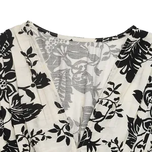 Detail view of V-neckline featuring elegant black and white tropical floral pattern print