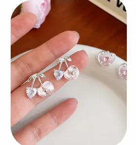 Vue macro de boucles d'oreilles cerises roses avec pierre en cœur et tiges argent