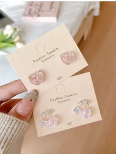 Vue détaillée des boucles d'oreilles cerise et cœur roses sur carte de support