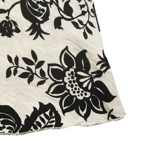 Close-up of black floral print on beige textured fabric with neat overlock stitching