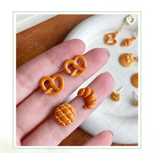Dettaglio di orecchini a forma di croissant e pretzel con finitura realistica