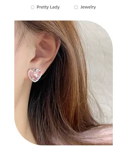 Gros plan de boucles d'oreilles cœur rose avec griffes argentées sur l'oreille