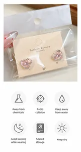 Vue détaillée de boucles d'oreilles cœur roses emballées avec icônes de soin