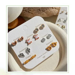 Set di sette paia di orecchini a lobo a cartone animato con orso e caramelle su carta bianca