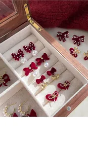 Detailed close-up of velvet bow and heart earrings collection in red and gold