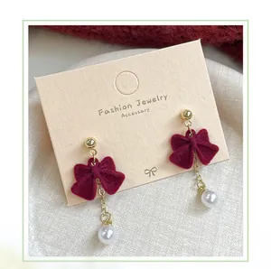 Detail of red flocked bow earrings with elegant pearl drops on jewelry card