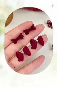 Close-up of wine red flocked bow earrings set with elegant velvet texture and gold metallic accents