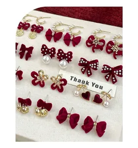 Macro detail of red flocked bow earrings with gold Fu character and pearl accents