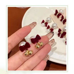 Close-up of velvet bow earrings with pearls and golden bells for a festive look