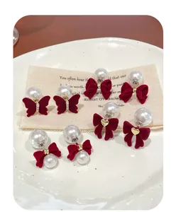 Detailed macro view of burgundy velvet bow earrings with pearls and butterfly charms
