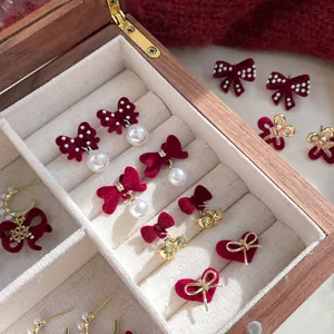 Elegant burgundy velvet bow earrings with pearls and gold accents in a jewelry box